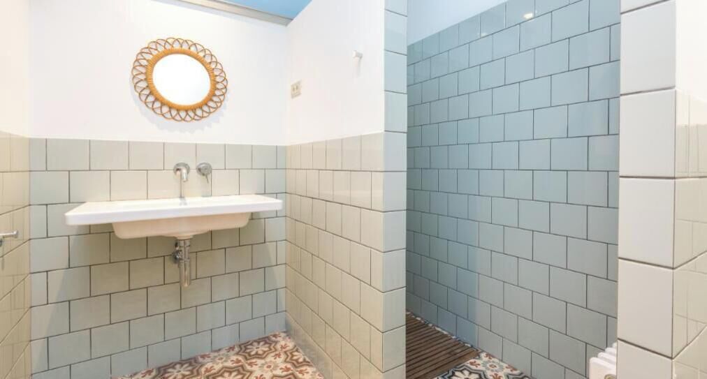 A bathroom with a sink, patterned floor, and light blue tiles.