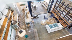 A spacious living area with a high ceiling, a dining area with a table and chairs, and a kitchen area with a counter and stools. - Mirador in Llafranc With 4 Bedrooms and 4 Bathrooms (Palafrugell)