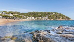 A coastal beach with clear waters, rocky shoreline, and buildings on a hillside. - Mirador in Llafranc With 4 Bedrooms and 4 Bathrooms (Palafrugell)