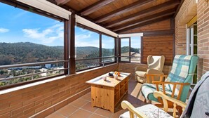 Un balcon avec une table en bois, deux chaises et un canapé.