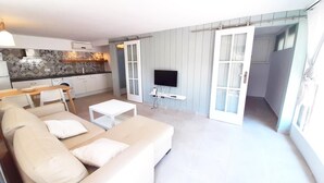 A modern living room with a beige sofa, a white coffee table, and a flat-screen TV mounted on the wall. - Gregal in Llafranc With 2 Bedrooms and 1 Bathrooms (Palafrugell)