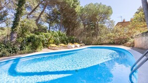 A swimming pool with lounge chairs and a stone wall. - Carena 1 in Llafranc (Palafrugell)