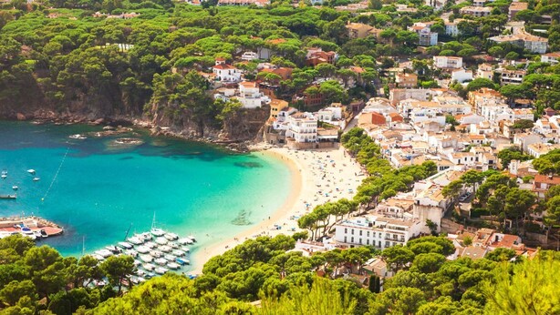A coastal town with a beach, boats, and densely packed buildings. - Carena 1 in Llafranc (Palafrugell)