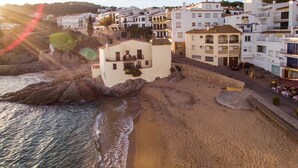 A coastal town with white buildings, a sandy beach, and rocky outcrops. - Carena 1 in Llafranc (Palafrugell)