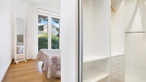 Egy hálószoba, melyben egy virágmintás ágytakaróval borított ágy, egy fehér szekrény található, és az ablakon át zöld tájra nyílik kilátás.