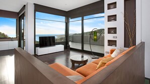 Una sala de estar moderna con un ventanal grande, un televisor de pantalla plana, un sofá y una mesita de centro.