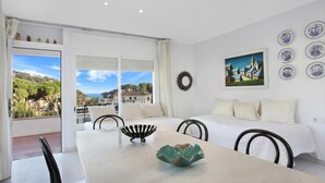 A room with a balcony, a dining table with chairs, a sofa, and a painting on the wall. - Pandora 2 in Llafranc (Palafrugell)