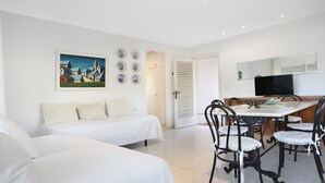 A hotel room with two beds, a dining table with chairs, a TV, and a painting on the wall. - Pandora 2 in Llafranc (Palafrugell)