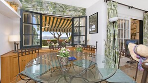 A dining area with a glass table, chairs, and a view through large windows. - Ses Brises 28 in Llafranc (Palafrugell)