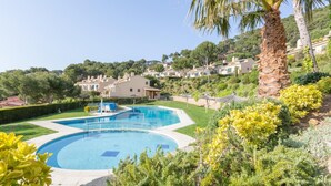 A residential area with a large swimming pool surrounded by lush greenery and palm trees. - Ses Brises 28 in Llafranc (Palafrugell)