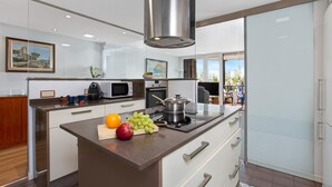 A modern kitchen with a central island, stainless steel appliances, and a view to the outdoors. - Sa Palomera in Blanes (Blanes)