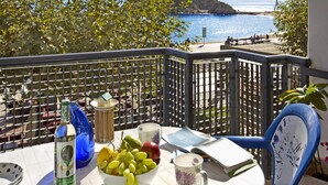 A balcony with a table set with a bottle, a bowl of fruit, and a mug, overlooking a beach and the sea. - Sa Palomera in Blanes (Blanes)