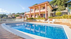 A two-story building with a swimming pool, outdoor seating, and a stone wall. - Vila Maer in Blanes With 5 Bedrooms and 2 Bathrooms (Blanes)