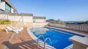 A rooftop swimming pool with lounge chairs, a stone wall, and a view of the sea. - Vila Maer in Blanes With 5 Bedrooms and 2 Bathrooms (Blanes)