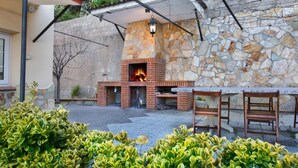 Un espacio al aire libre con patio, pared de piedra, chimenea de ladrillo y mobiliario de madera.
