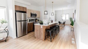 Eine moderne Küche mit Edelstahlgeräten, Holzschränken und einer zentralen Kochinsel mit Barhocker.