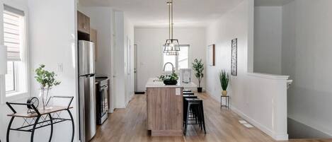 A modern kitchen with a central island, stainless steel appliances, and a pendant light.