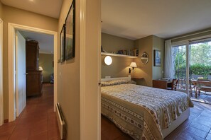 A bedroom with a bed, a desk, a chair, a bookshelf, and a window with a view of greenery. - Cliper L1 in Llafranc (Palafrugell)