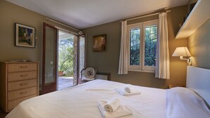 Ein Schlafzimmer mit Bett, Kommode, Stuhl und einem fenster mit Vorhängen.