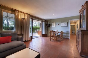 A living room with a sofa, a dining table with chairs, and a kitchen area with cabinets. - Cliper L1 in Llafranc (Palafrugell)