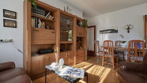 A room with a wooden bookshelf, a dining table with chairs, and a leather sofa. - Masso in Llafranc With 3 Bedrooms and 1 Bathrooms (Palafrugell)