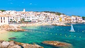 A coastal town with buildings along the shore, clear blue water, and a sailboat. - Masso in Llafranc With 3 Bedrooms and 1 Bathrooms (Palafrugell)