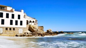 A coastal building with a stone facade, large rock formations, and a clear blue sky. - Llado 2 in Calella de Palafrugell (Palafrugell)
