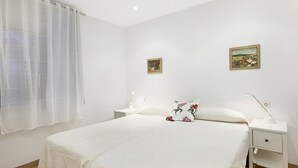 A bedroom with a large bed, two nightstands, a white lamp, and two framed pictures on the wall. - Ancora 01 in Llafranc (Palafrugell)