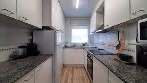 Una cucina compatta con mobili bianchi, un piano di lavoro nero, un lavello in acciaio inossidabile e un forno a microonde.