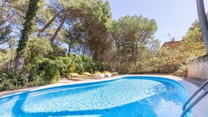 A swimming pool with lounge chairs and trees in the background. - Carena 2 in Llafranc (Palafrugell)