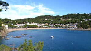 A coastal town with a beach, rocky shoreline, and a boat in the water. - Carena 2 in Llafranc (Palafrugell)