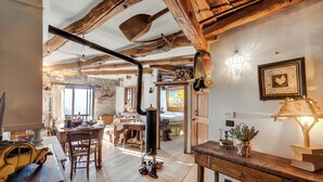 A rustic interior with exposed wooden beams, a dining area with a table and chairs, a fireplace, and a cozy atmosphere. - Grange Romantic Retreat Mountain View (Sauze di Cesana)