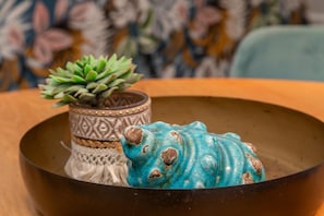 Eine dekorative Schale mit einem blauen Keramikschwein und einem gemusterten Topf mit einer Sukkulente.