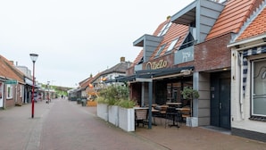 Une rue où se trouve un restaurant appelé « OZieZo », doté d’une terrasse et d’une façade en briques.