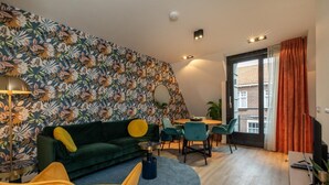 Un salon moderne avec un canapé vert, un fauteuil jaune et un coin repas doté de chaises turquoise.