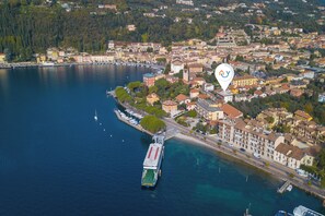 An aerial view of a coastal town with a prominent waterfront, a large cruise ship docked, and a mix of residential and commercial buildings. - Maderno Sweet Home in Toscolano Maderno (Toscolano Maderno)