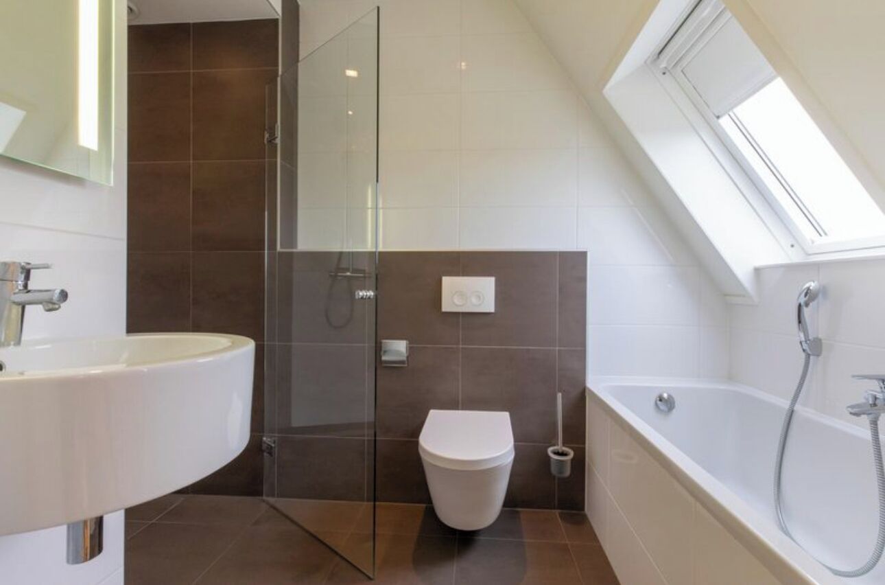 A modern bathroom with a glass shower enclosure, a white sink, a toilet, and a bathtub.