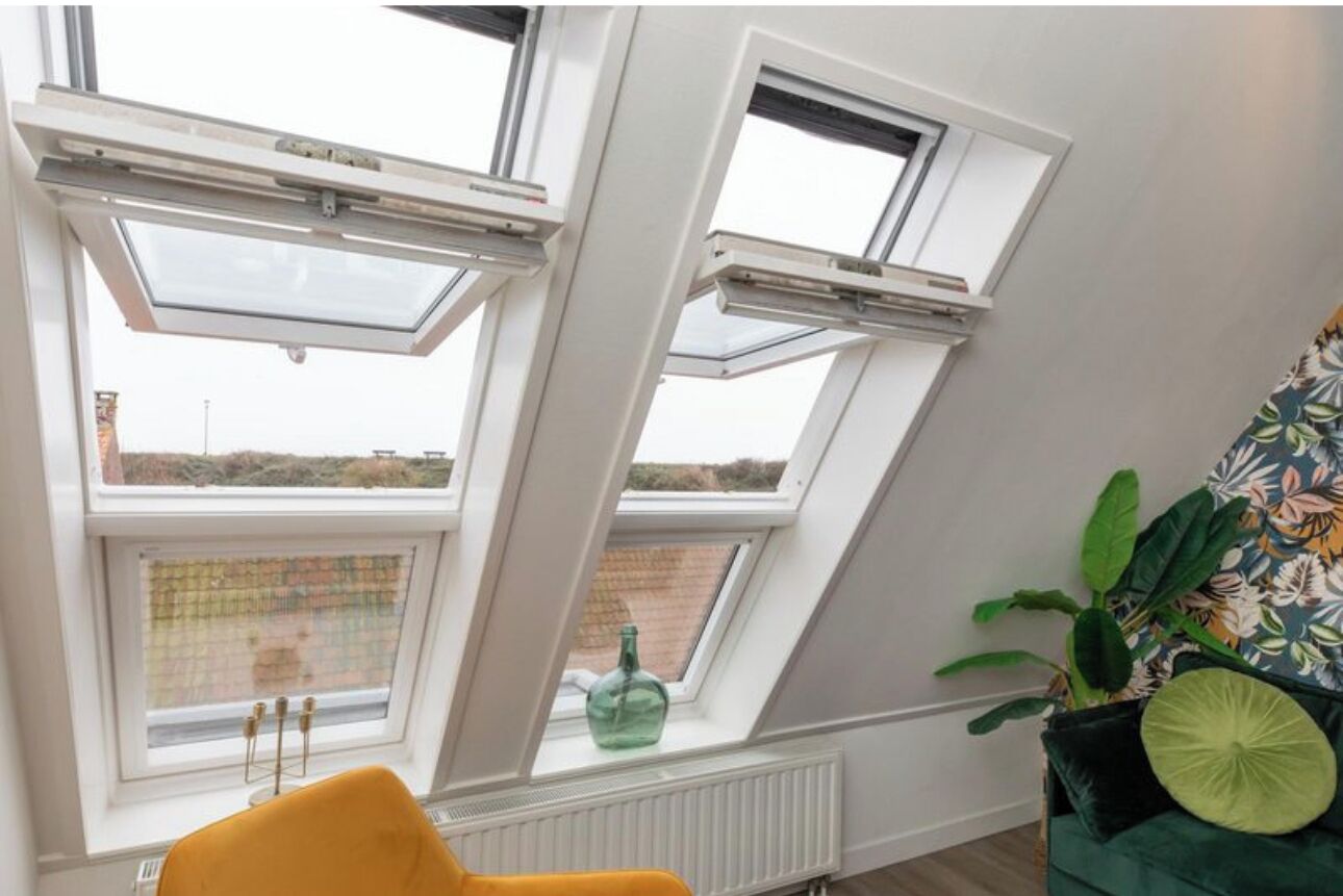 A room with skylights, a radiator, a yellow chair, and a green plant.