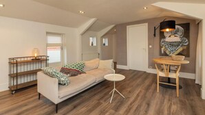 Una sala de estar con un sofá, una mesita redonda y una lámpara decorativa.
