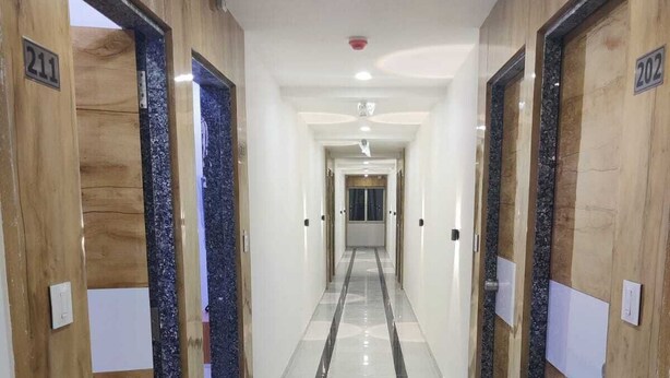 A hallway with wooden doors numbered 211 and 202, leading to rooms. - HOTEL SAVERA (Ahmedabad)