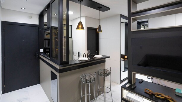 Un baño moderno con un tocador negro, dos lámparas colgantes y un espejo.