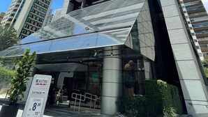 Un edificio alto y moderno con entrada de vidrio y un letrero que indica un área de estacionamiento.