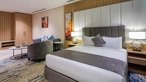 A hotel room with a large bed, a sofa, a small table, and a cabinet. - Rhenium Hotel (Riyadh)