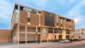 A modern hotel with a prominent 'HOTEL' sign, a large entrance with a covered area, and a parking lot with cars. - Rhenium Hotel (Riyadh)