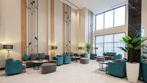 A spacious lobby with modern furniture, large windows, and a marble floor. - Rhenium Hotel (Riyadh)