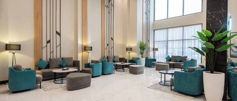 A spacious lobby with modern furniture, large windows, and a marble floor.