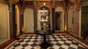 A checkered floor, a round table with a vase, and arched doorways. - Aakash Heritage Haveli (Jodhpur)