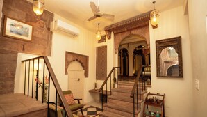 A staircase with a wooden finish, a chandelier, and a wall-mounted air conditioner. - Aakash Heritage Haveli (Jodhpur)