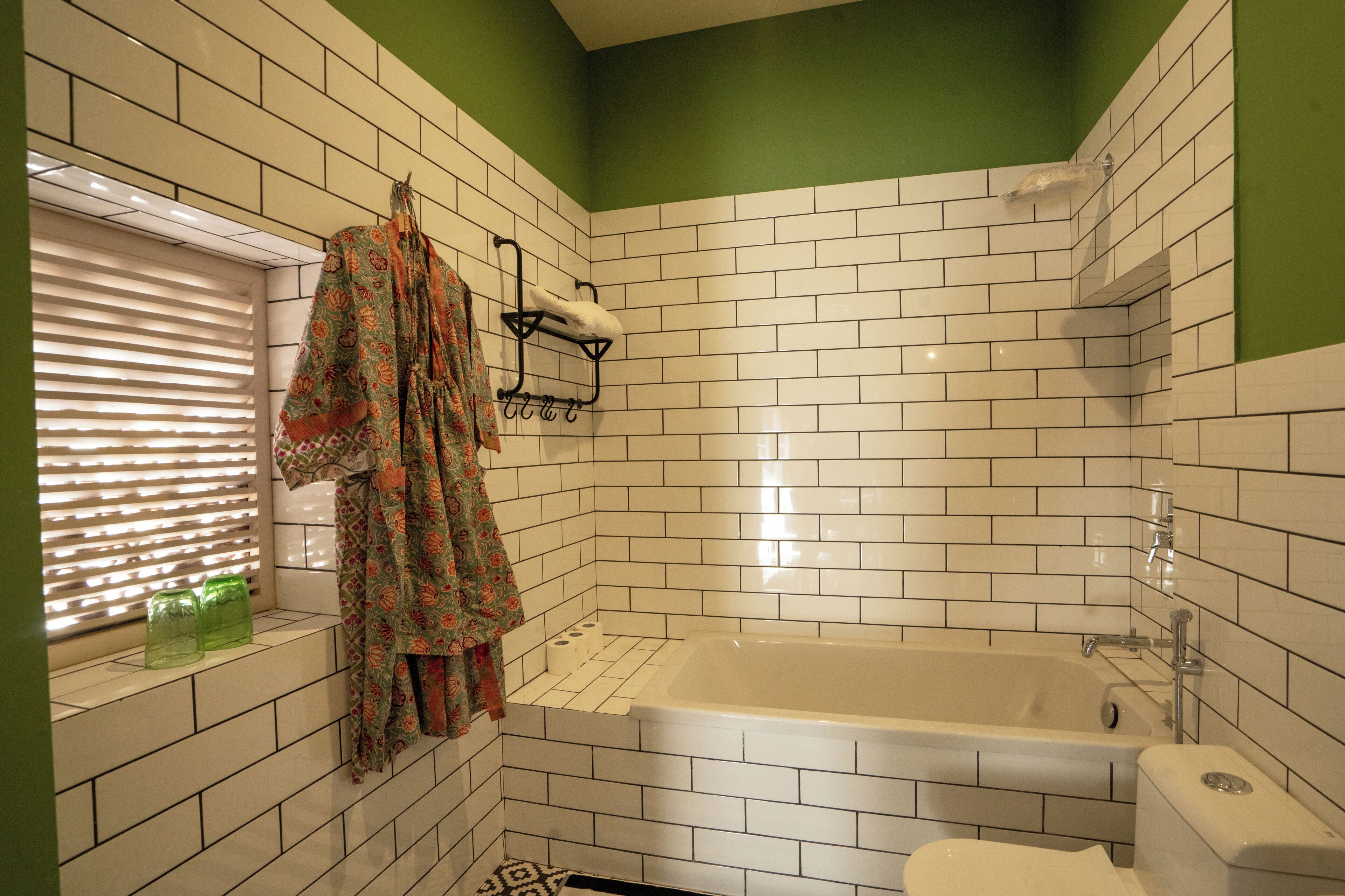 A bathroom with white tiled walls, a bathtub, and a toilet.