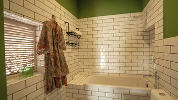A bathroom with white tiled walls, a bathtub, and a toilet.